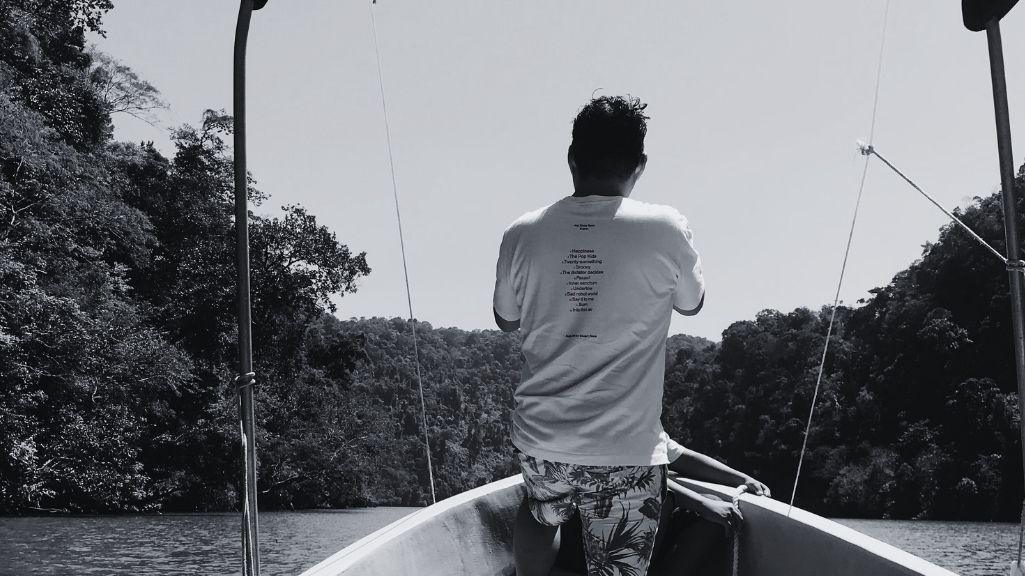 Persona navegando en bote por el río Dulce, Livingston Guatemala, rodeado de naturaleza tropical